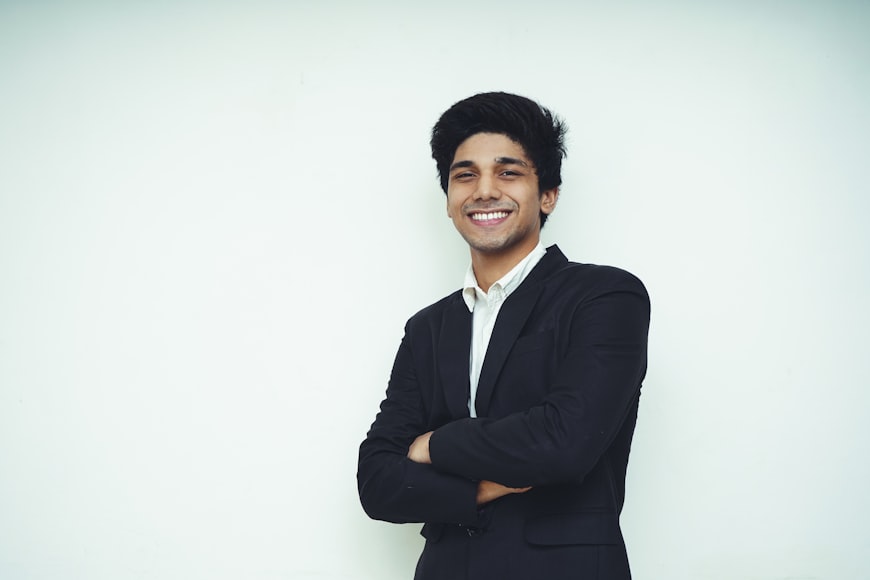 Young Business Man wearing formal Clothes standing on a white wall Man in black suit standing in front of white wall